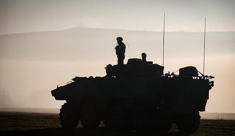 Un soldat contemplant un coucher de soleil sur un véhicule blindé de combat d’infanterie