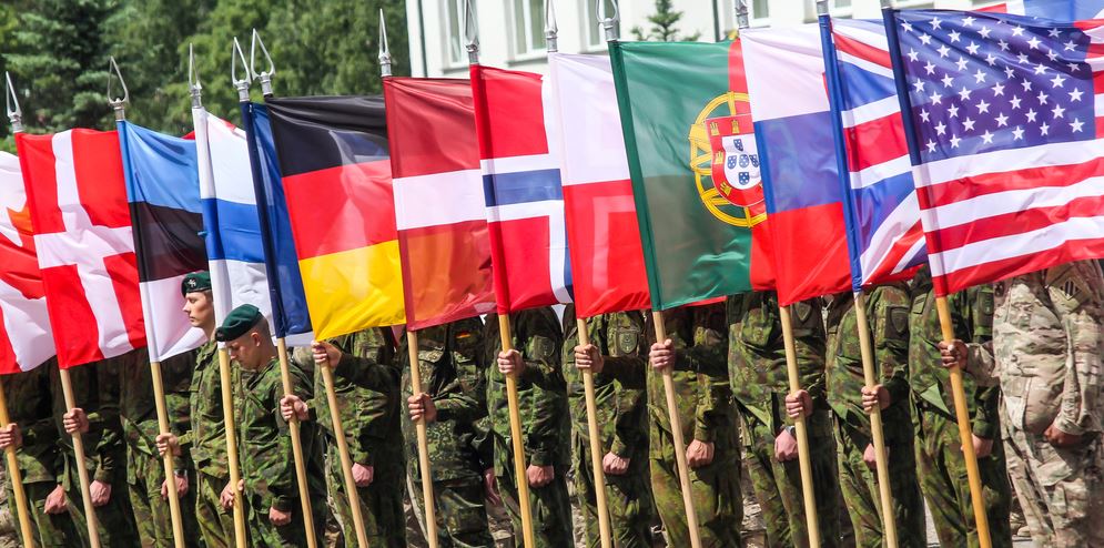 RUKLA, LITHUANIA - JUNE 8, 2015: NATO soldiers holding alliance flags