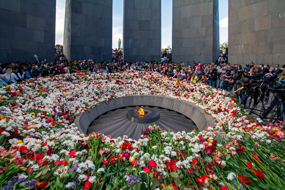 Yerevan, Armenia - April 24, 2018: Armenians laying flowers at the eternal flame in the center of the twelve slabs of Armenian Genocide memorial 