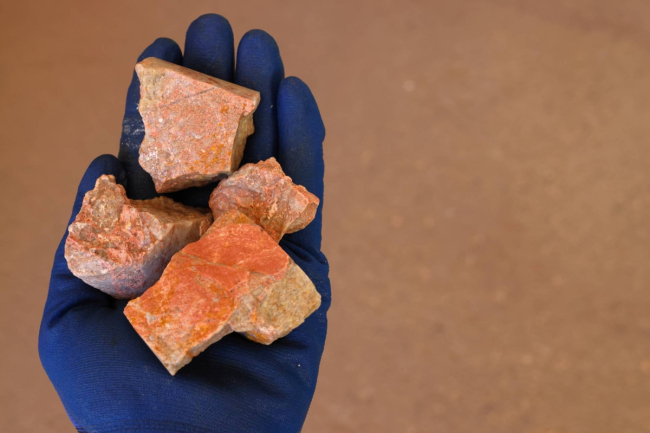 Xenotime ore held in hand with a blue protective glove