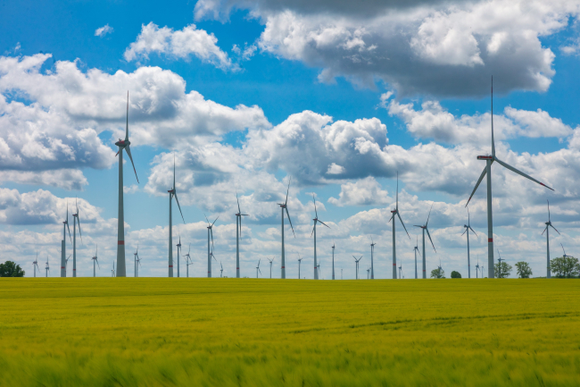 Modern wind turbines spinning over lush green fields in rural Germany. A powerful symbol of the Energiewende and Germany's response to climate change and the energy transition.