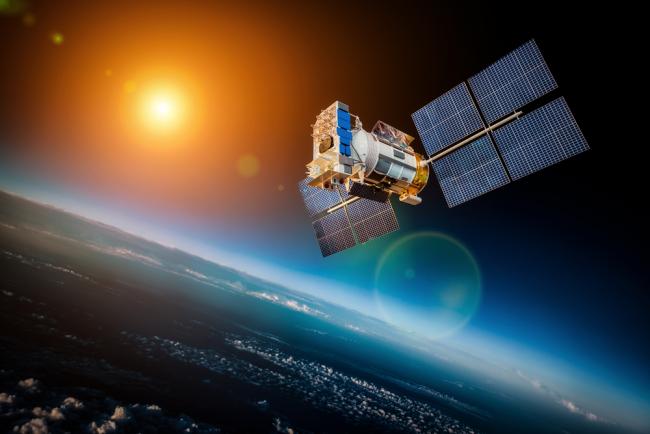 Space satellite orbiting earth on starry sun background
